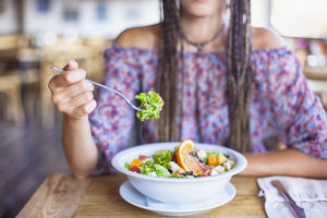 Woman Eating Salad in Restaurant